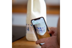 Image A hand scanning a QR code on a milk carton.